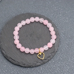 Bracelet en perles roses translucides avec pendentif cœur doré sur support pierre