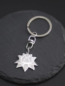Macro shot of stainless steel lotus pendant keychain with detailed etching on stone background