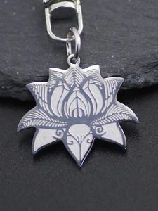 Macro detail of stainless steel lotus pendant with etched petal textures on stone surface