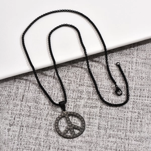 Détail du pendentif signe de paix noir mat avec texture à pois et chaîne à billes