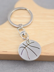 Detailed macro shot of a shiny silver basketball pendant keychain on a wooden surface