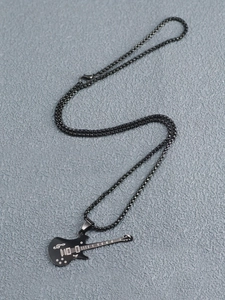Nahaufnahme eines schwarzen E-Gitarren-Anhängers mit Noten an einer Punk-Streetwear-Kette
