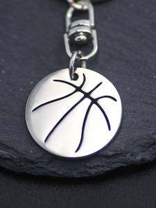 Macro shot of silver basketball pendant keychain with lobster clasp on slate stone