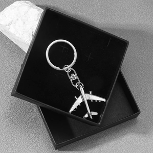Sleek silver metal airplane keychain on a black gift box with a modern business look