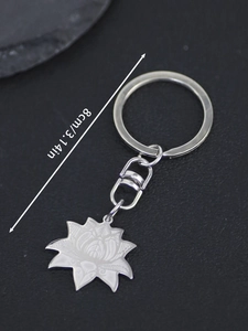 Detail of silver stainless steel lotus pendant keychain with carved petals on black stone