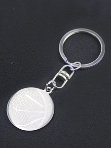 Close-up of polished silver basketball pendant keychain with textured laser engraving