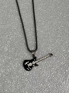 Detailansicht der schwarzen E-Gitarre Halskette mit weißen Notenmustern und Kette