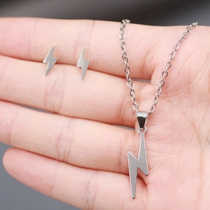 Detailed view of silver lightning bolt pendant and matching stud earrings on palm