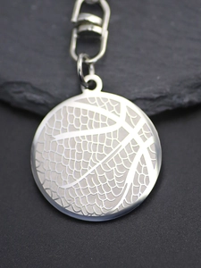 Macro detail of silver basketball pendant keychain with textured finish and spring clasp