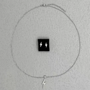 Detail view of silver stainless steel lightning bolt pendant necklace and stud earrings set