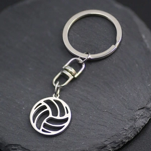 Polished stainless steel volleyball hollow pendant keychain on dark stone background