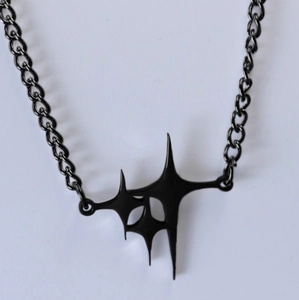 Detail of matte black gothic star pendant with chunky chain on white background