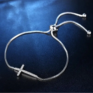Macro shot of silver-tone cross bracelet featuring sparkling zircon and adjustable slider