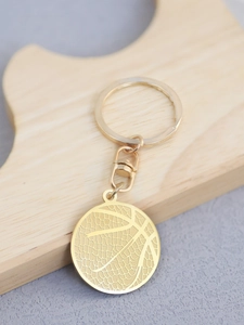 Detail of golden basketball pendant keychain with textured finish on wooden display