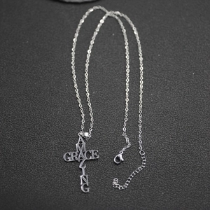 Vue macro du pendentif croix Amazing Grace en acier inoxydable argenté poli
