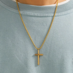 Close-up of a polished gold cross pendant on a matching box chain over blue fabric