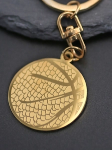 Macro detail of golden basketball keychain pendant with textured lines and metallic finish