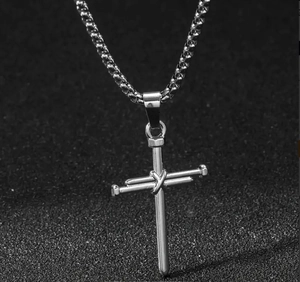 Detail of silver titanium steel cross pendant with industrial nail design on black background