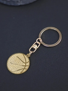 Macro detail of 3D textured golden basketball pendant keychain on black leather surface
