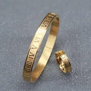 Macro detail of gold stainless steel bracelet and ring with Roman numeral engravings