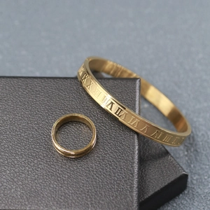 Detailed close-up of gold stainless steel bangle and ring set with Roman numerals on leather box