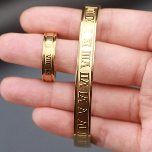Detail shot of gold stainless steel bracelet and ring with engraved Roman numerals