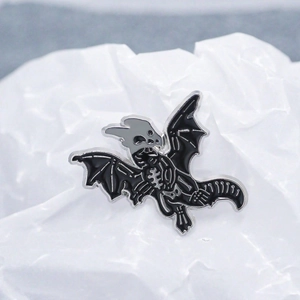 Detailed close-up of dark style flying dragon skeleton enamel pin on white background