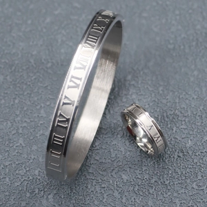 Detail of silver stainless steel jewelry set with Roman numeral engravings and brushed finish