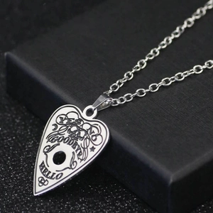 Polished stainless steel necklace with etched heart-shaped Ouija board pendant on a jewelry box