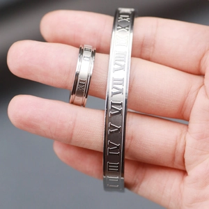 Detail of silver stainless steel ring and open cuff bracelet with Roman numeral engravings