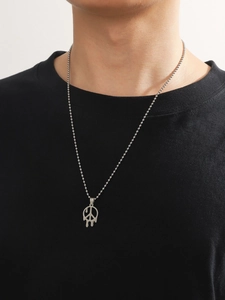 Détail du collier pendentif peace sign argenté au style fondu sur un t-shirt noir