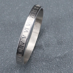 Macro shot of silver stainless steel cuff featuring engraved roman numerals on gray background
