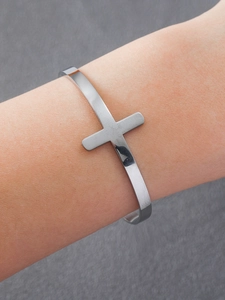 Détail du bracelet jonc croisé en argent avec finition polie sur le poignet d'un mannequin