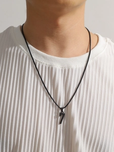 Détail d'un collier pendentif chiffre 7 noir mat porté sur un t-shirt blanc texturé