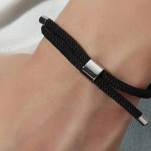 Bracelet tressé noir minimaliste avec breloques en métal argenté porté avec style au poignet