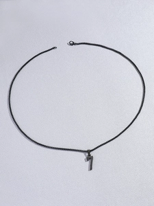 Détail d'un collier en acier inoxydable noir avec un pendentif chiffre 7 au style minimaliste
