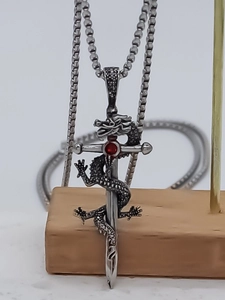 Macro detail of dragon wrapped sword necklace featuring a sparkling red gemstone