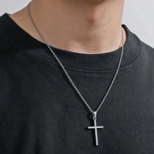 Minimalist silver cross necklace with white zircon stones on a model wearing a black t-shirt