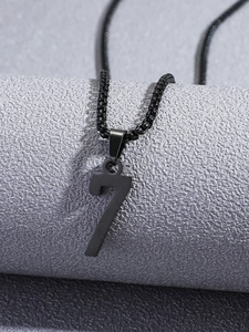 Vue macro d'un pendentif chiffre 7 noir mat sur une chaîne à perles minimaliste