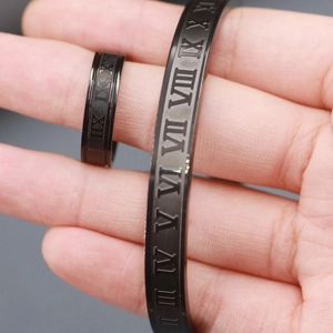 Macro shot of black stainless steel ring and cuff bracelet with Roman numeral engravings