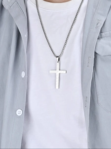 Close-up of minimalist silver cross pendant necklace with textured detail on model