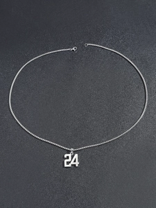 Détail du pendentif argent numéro 24 avec chaîne vénitienne sur fond sombre texturé