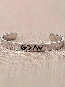 Close-up of silver stainless steel cuff bracelet with engraved minimalist symbols