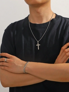 Parure de bijoux argentés avec collier croix, bracelet gourmette et bague portés par modèle