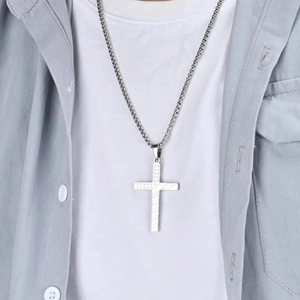 Mens silver cross necklace with textured pendant design on a blue shirt and white tee