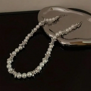 Silver-tone wire mesh and pearl splice necklace displayed on a modern reflective surface