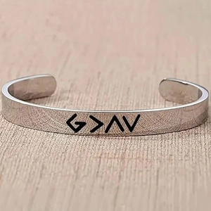 Minimalist silver open cuff bracelet engraved with G > ^ V religious symbol on wood surface