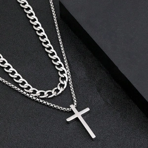 Detail of silver double-layered set featuring a Cuban link chain and a cross pendant necklace