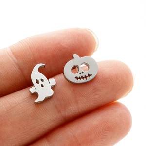 Detail of hand-held silver skull and pumpkin earrings for Halloween punk style