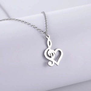 Polished stainless steel G-clef and heart musical note pendant necklace on white background